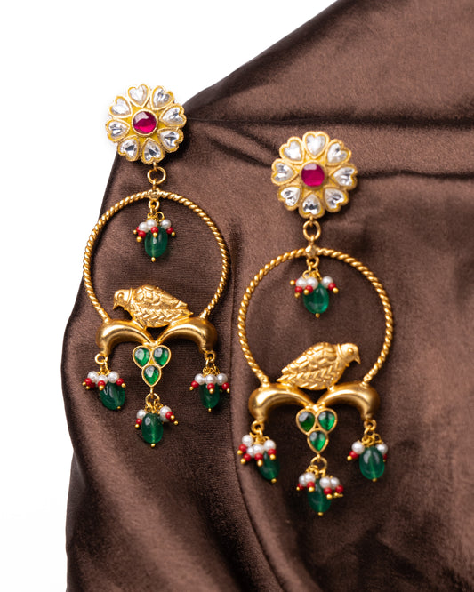 Golden bird earrings with green and pink stones.